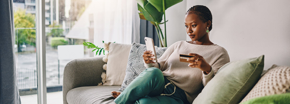 Black woman looking at her mobile phone and credit card