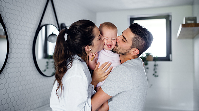 mother and father kissing child