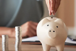 young girl putting coins into her piggy bank