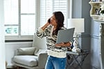 woman holding laptop on her hip while talking on the phone