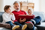 older man reading to two small children