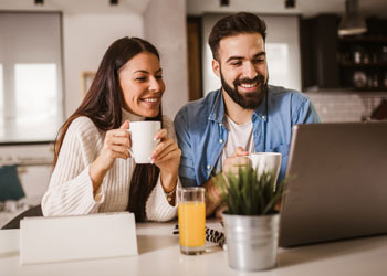 young couple drinking coffee and looking at a laptop computer