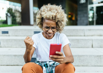woman excitedly looking at mobile phone