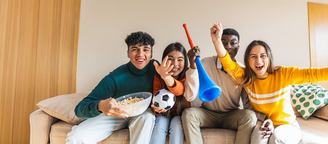 people cheering while watching a soccer match from home