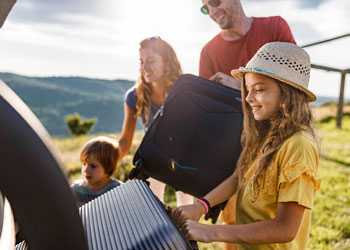 family of four loading suitcases into vehicle