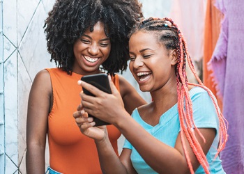 two smiling women looking at a mobile phone