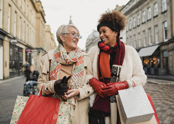 woman walking together down the street holdin shopping bags