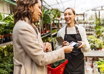 woman tapping card within plant nursery