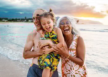 older couple on beach holding child