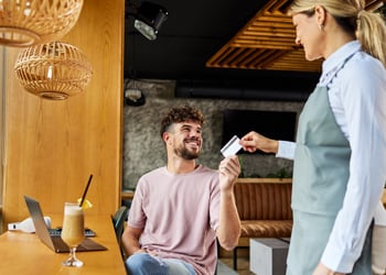 man handing his credit card to waitress