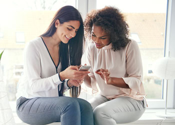 woman sitting together looking at a phone