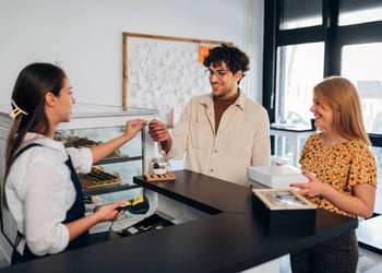 woman and man using debit card to pay at a cafe