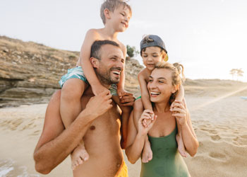 family of four smiling on the beach