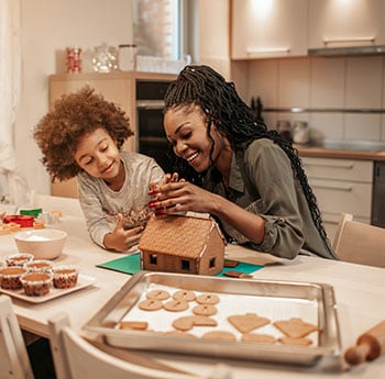 Mother and daughter building gingerbread house