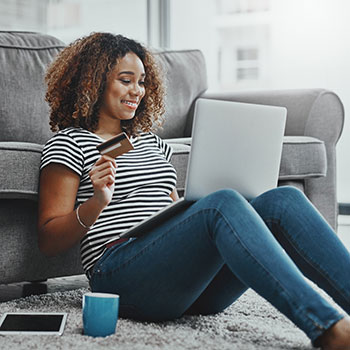 Young woman holding card and using laptop computer