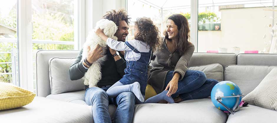 family and dog on couch in home