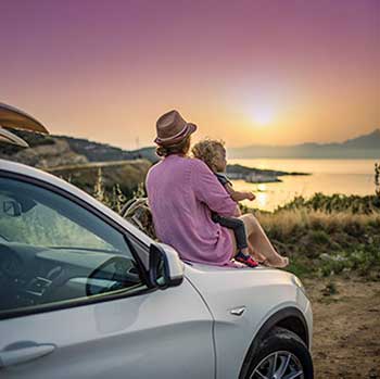 Woman and child looking at sunset on car