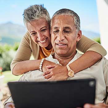 couple smiling and looking at electronic tablet