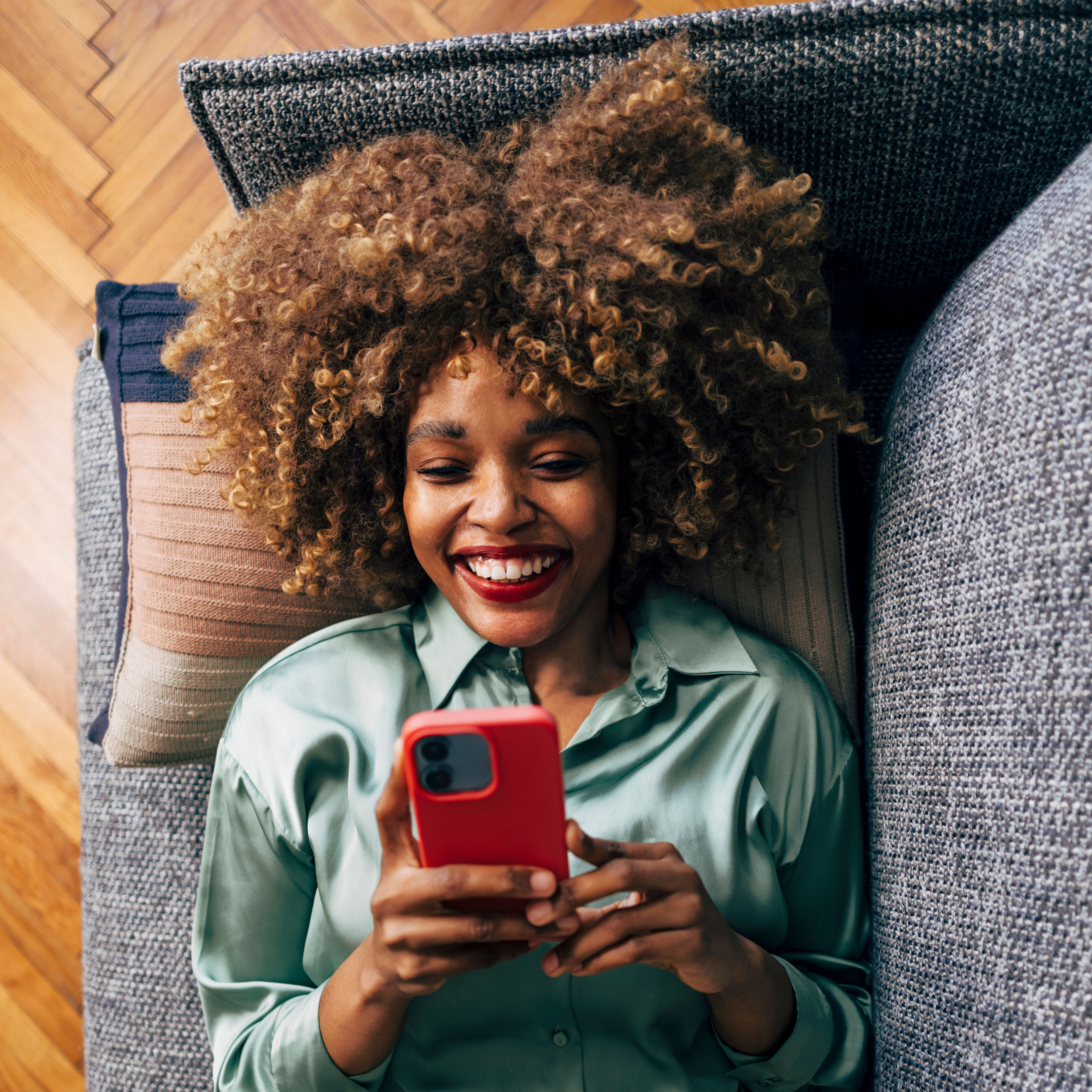woman laying on couch and looking at phone