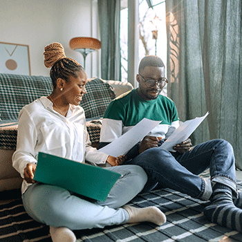 Couple sitting on floor looking at paperwork