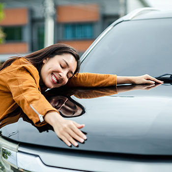 woman laying on hood of car and smiling
