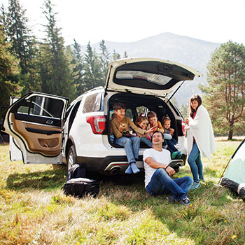family sitting on trunk of car
