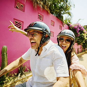 couple riding on moped and smiling
