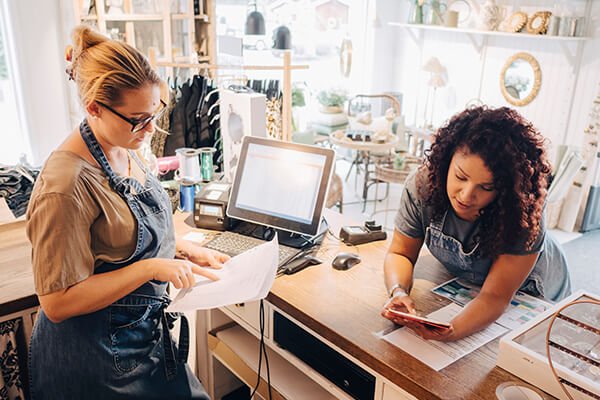 colleagues doing online money transfer at checkout counter in store