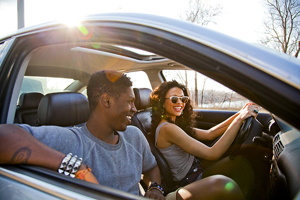 young couple in a car driving with the windows down