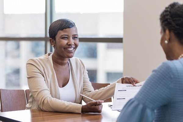 female loan specialist providing female customer with a loan application