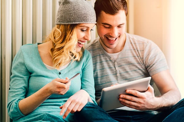 young couple sitting on floor in a living room at home  and shopping online with digital tablet