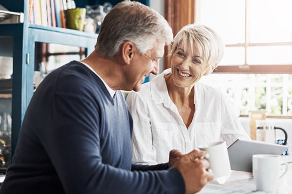 a mature couple having coffee while using their digital tablet at home