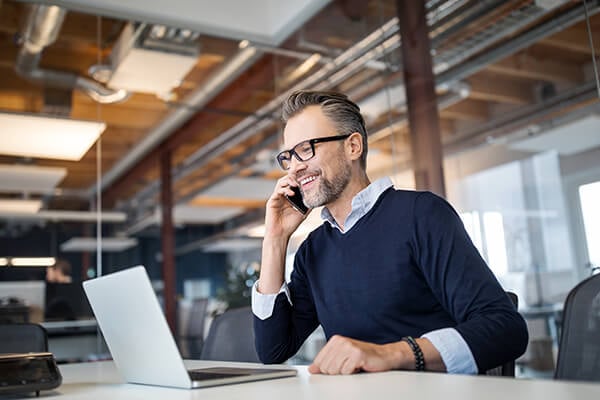  man sitting at table and doing wire transfer on laptop